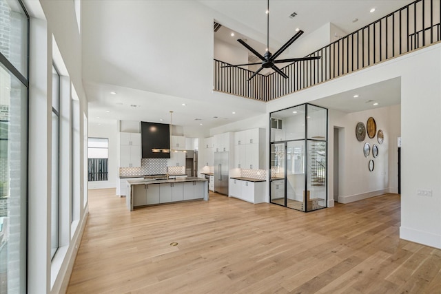 kitchen with tasteful backsplash, light wood-style floors, a ceiling fan, white cabinets, and stainless steel built in refrigerator