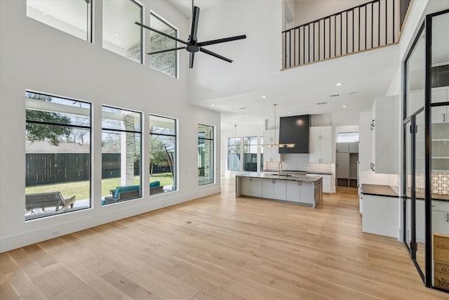 unfurnished living room featuring recessed lighting, light wood-style floors, a sink, ceiling fan, and baseboards