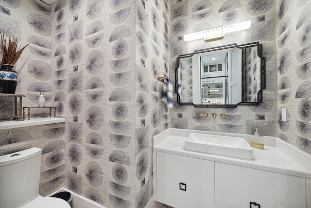 bathroom with vanity, toilet, and wallpapered walls