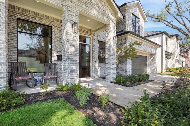 entrance to property with driveway, brick siding, and an attached garage