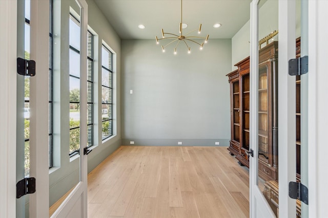 unfurnished room with light wood-style flooring, baseboards, a notable chandelier, and recessed lighting