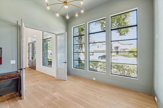 interior space with light wood finished floors, an inviting chandelier, and a healthy amount of sunlight