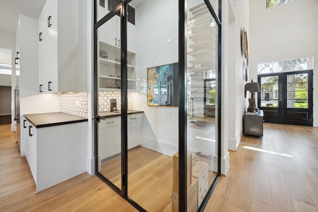 interior space featuring a towering ceiling, light wood-type flooring, and french doors