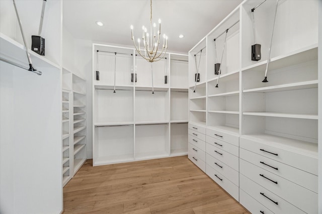 walk in closet featuring light wood finished floors and an inviting chandelier