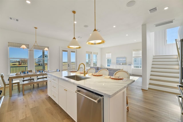 kitchen featuring dishwasher, light wood-style flooring, a sink, and visible vents