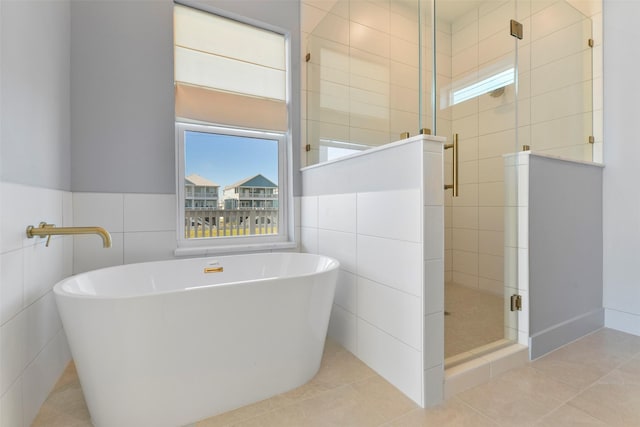 full bath with a freestanding tub, a shower stall, tile walls, and tile patterned floors