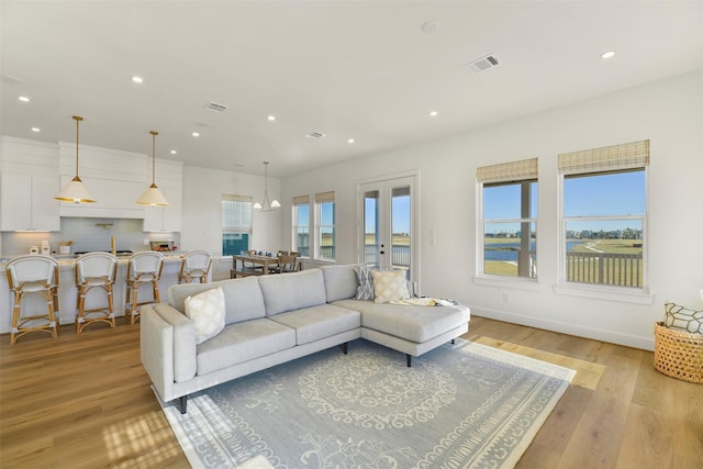 living room with baseboards, light wood-type flooring, visible vents, and recessed lighting