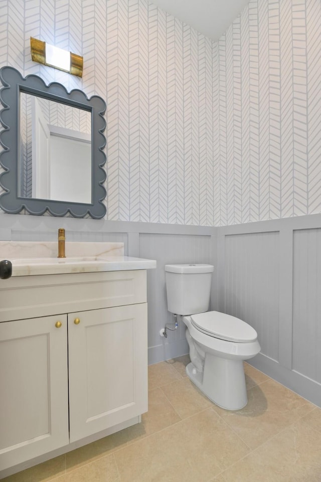 half bathroom featuring vanity, tile patterned flooring, and toilet