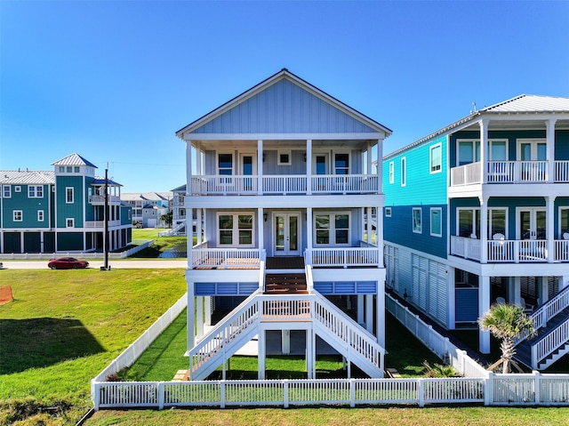 back of property featuring french doors, a porch, a lawn, stairway, and fence