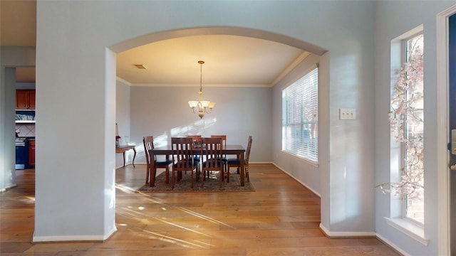 dining area with baseboards, visible vents, light wood finished floors, arched walkways, and ornamental molding