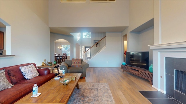 living area with stairs, a high ceiling, wood finished floors, and arched walkways