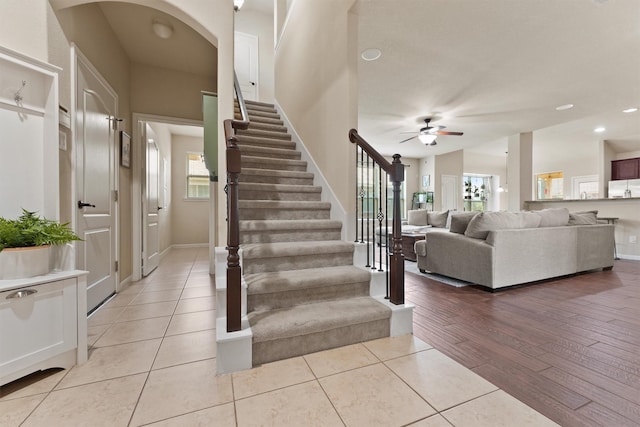 interior space featuring ceiling fan, baseboards, vaulted ceiling, stairway, and light wood finished floors