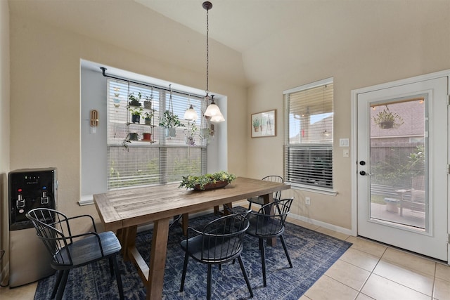 dining space with vaulted ceiling, light tile patterned floors, and baseboards