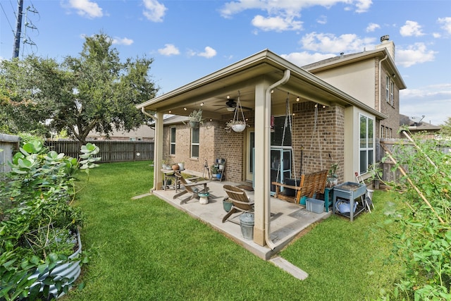 back of house featuring a patio, a fenced backyard, brick siding, a ceiling fan, and a lawn