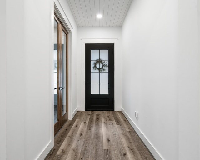 doorway featuring baseboards and wood finished floors