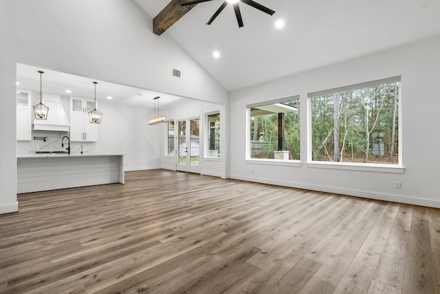 unfurnished living room featuring visible vents, a ceiling fan, wood finished floors, beamed ceiling, and baseboards