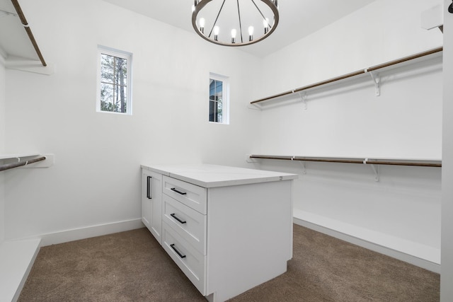 spacious closet featuring a chandelier and dark colored carpet