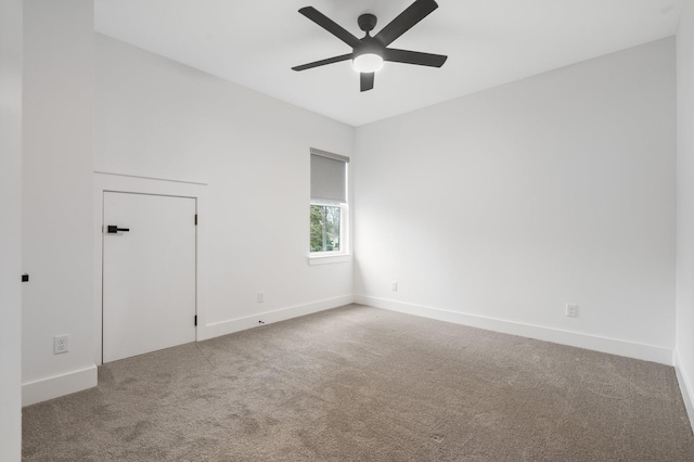 carpeted spare room with ceiling fan and baseboards