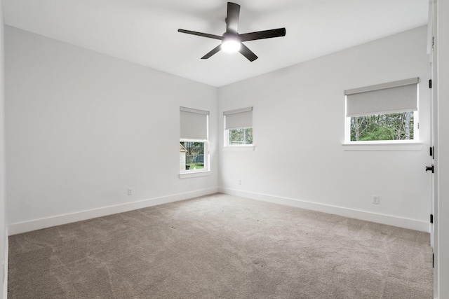 empty room with a ceiling fan, a wealth of natural light, carpet flooring, and baseboards