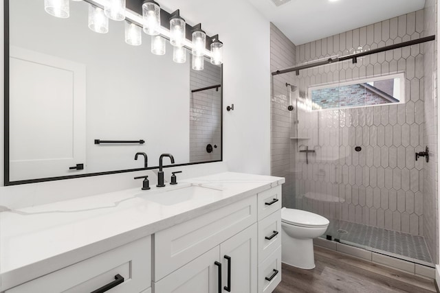 bathroom featuring toilet, wood finished floors, visible vents, vanity, and a shower stall