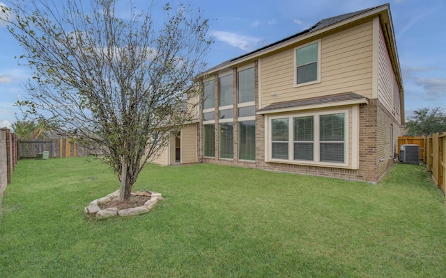 back of house featuring a yard, brick siding, cooling unit, and a fenced backyard