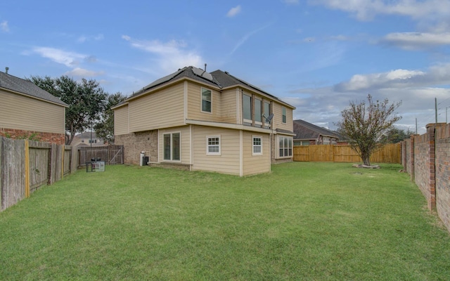 rear view of house featuring central AC unit, a lawn, and a fenced backyard