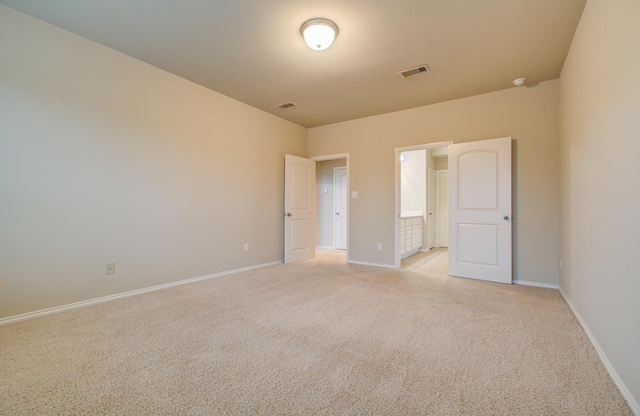 unfurnished bedroom featuring light carpet, ensuite bath, baseboards, and visible vents