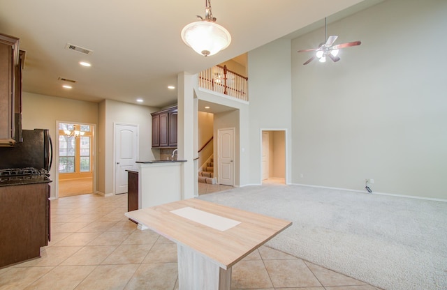 kitchen with dark countertops, light tile patterned floors, light carpet, and visible vents