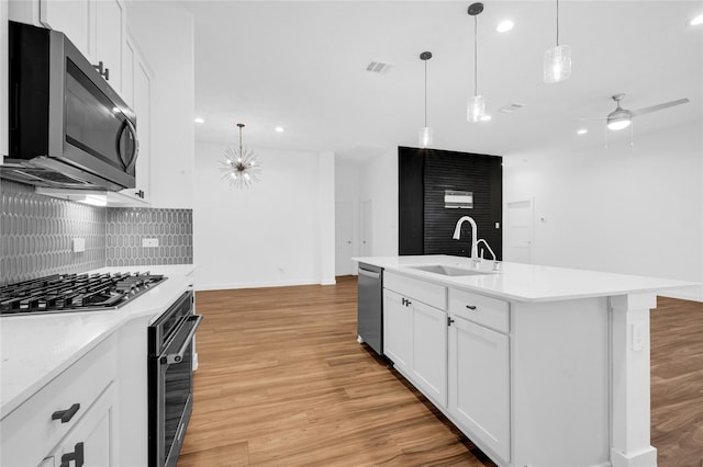 kitchen with visible vents, light wood-style flooring, appliances with stainless steel finishes, a sink, and backsplash