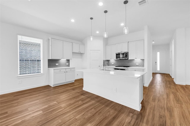 kitchen featuring light wood-style flooring, visible vents, light countertops, range, and stainless steel microwave