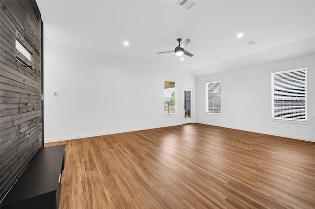 unfurnished living room featuring visible vents, light wood-style flooring, ceiling fan, wooden walls, and baseboards