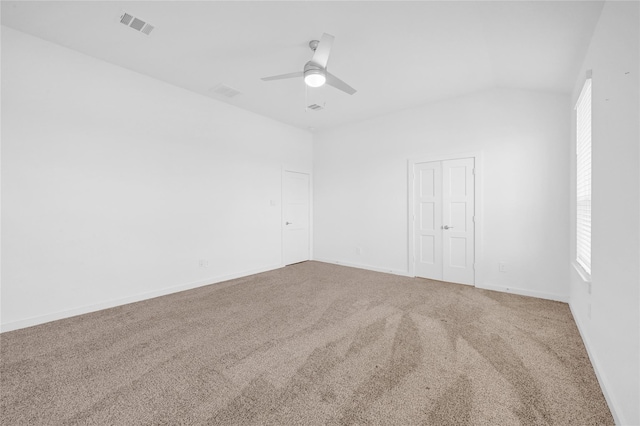 carpeted spare room featuring lofted ceiling, visible vents, ceiling fan, and baseboards