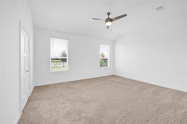 unfurnished room with carpet, lofted ceiling, visible vents, a ceiling fan, and baseboards