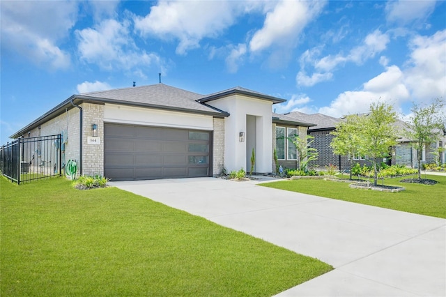 prairie-style home featuring concrete driveway, an attached garage, fence, a front lawn, and brick siding