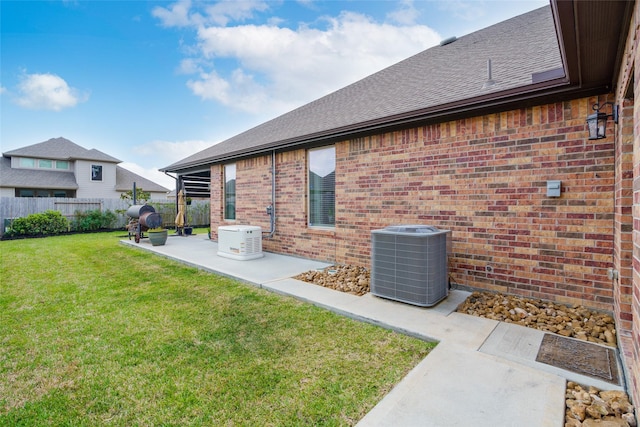 back of house with fence, central AC, brick siding, a patio area, and a yard
