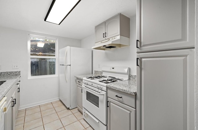 kitchen featuring white appliances, baseboards, light stone countertops, under cabinet range hood, and light tile patterned flooring