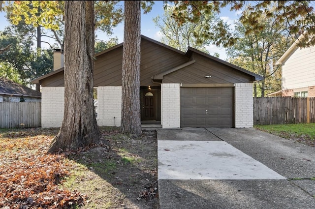 mid-century home featuring an attached garage, driveway, fence, and brick siding