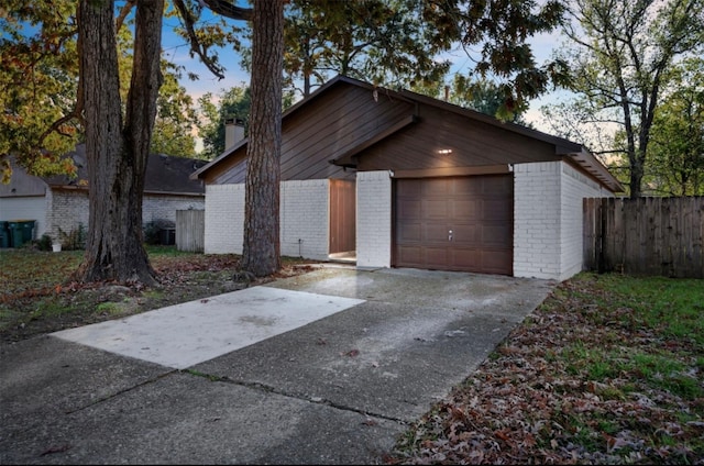 view of front facade with brick siding, a chimney, fence, a garage, and driveway