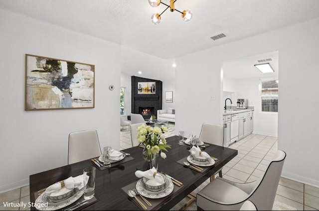 dining space featuring a fireplace, a notable chandelier, light tile patterned floors, visible vents, and baseboards