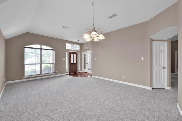 carpeted spare room featuring lofted ceiling, baseboards, visible vents, and a chandelier