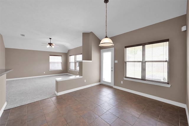 interior space featuring visible vents, lofted ceiling, dark colored carpet, baseboards, and ceiling fan