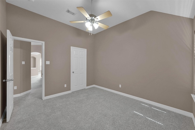 unfurnished bedroom featuring visible vents, arched walkways, carpet, and lofted ceiling