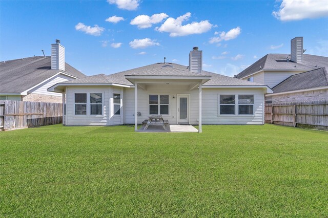 rear view of house with a patio area, a lawn, a chimney, and a fenced backyard