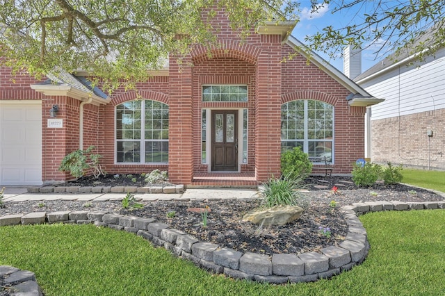 view of exterior entry featuring an attached garage and brick siding