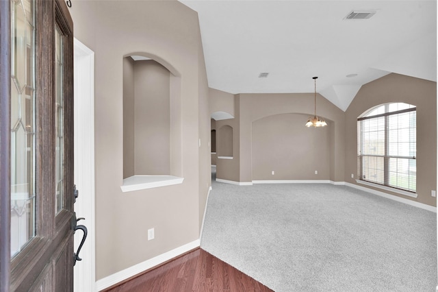 foyer featuring visible vents, baseboards, carpet, lofted ceiling, and an inviting chandelier