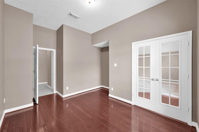 unfurnished room featuring visible vents, french doors, baseboards, and wood finished floors