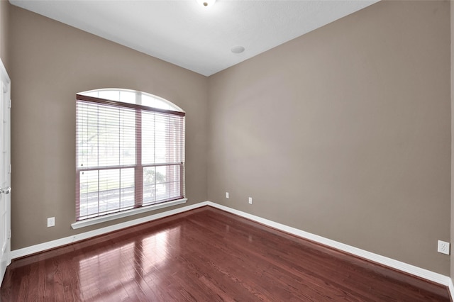 unfurnished room featuring baseboards and dark wood-style floors