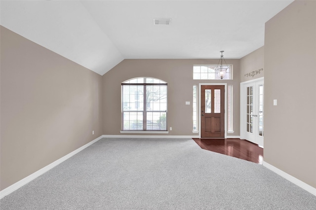 entrance foyer featuring baseboards, visible vents, vaulted ceiling, french doors, and dark colored carpet