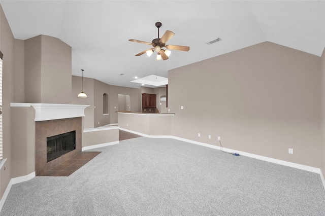 unfurnished living room with a tiled fireplace, vaulted ceiling, baseboards, and dark colored carpet