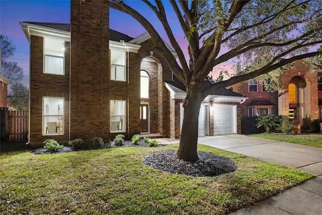 view of front of home with a lawn, driveway, fence, an attached garage, and brick siding